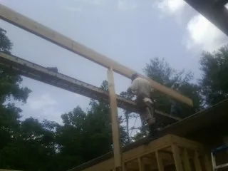 Carpenter setting a ridge beam over a new addition frame — Ice Dam Removal by Roofing Brothers in Mc Bain