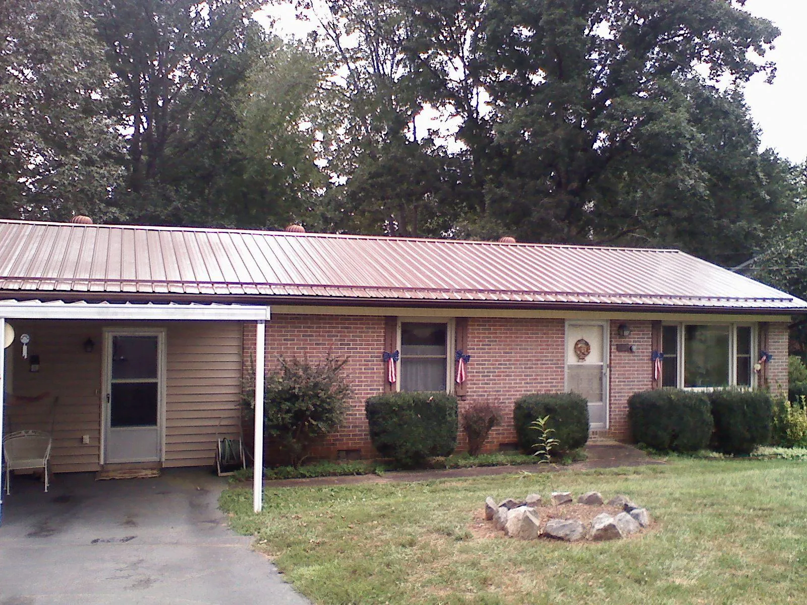 Bronze metal roof and carport on a brick ranch home — Roof Repair work by our crew in Mc Bain